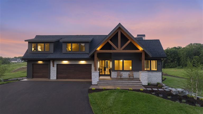A twilight aerial view of a suburban bungalow with a driveway and roof in a residential area.