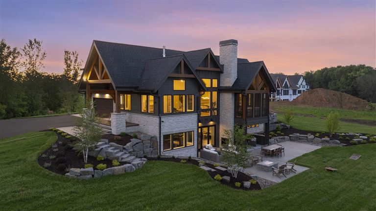Aerial view of an upscale suburban home at twilight with a spacious driveway and well-maintained lawn.
