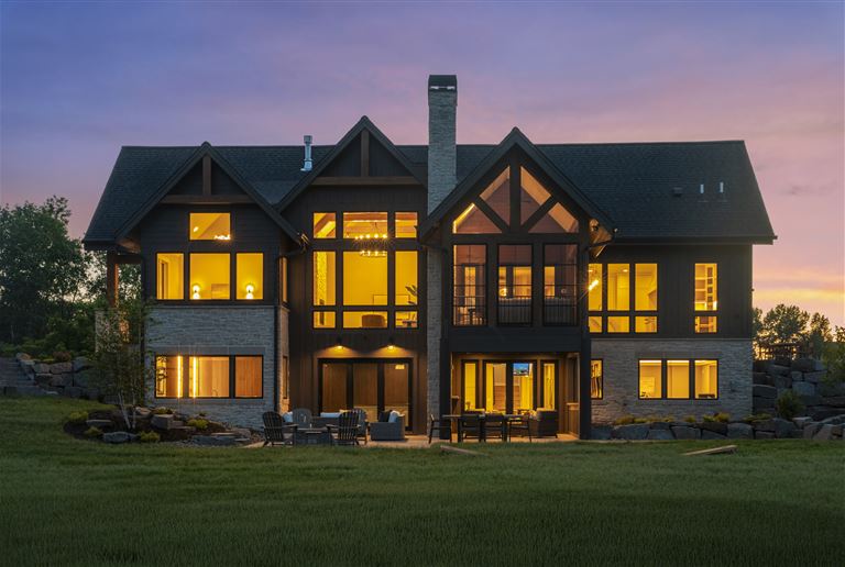 Elegant suburban home with a lawn and driveway at twilight.