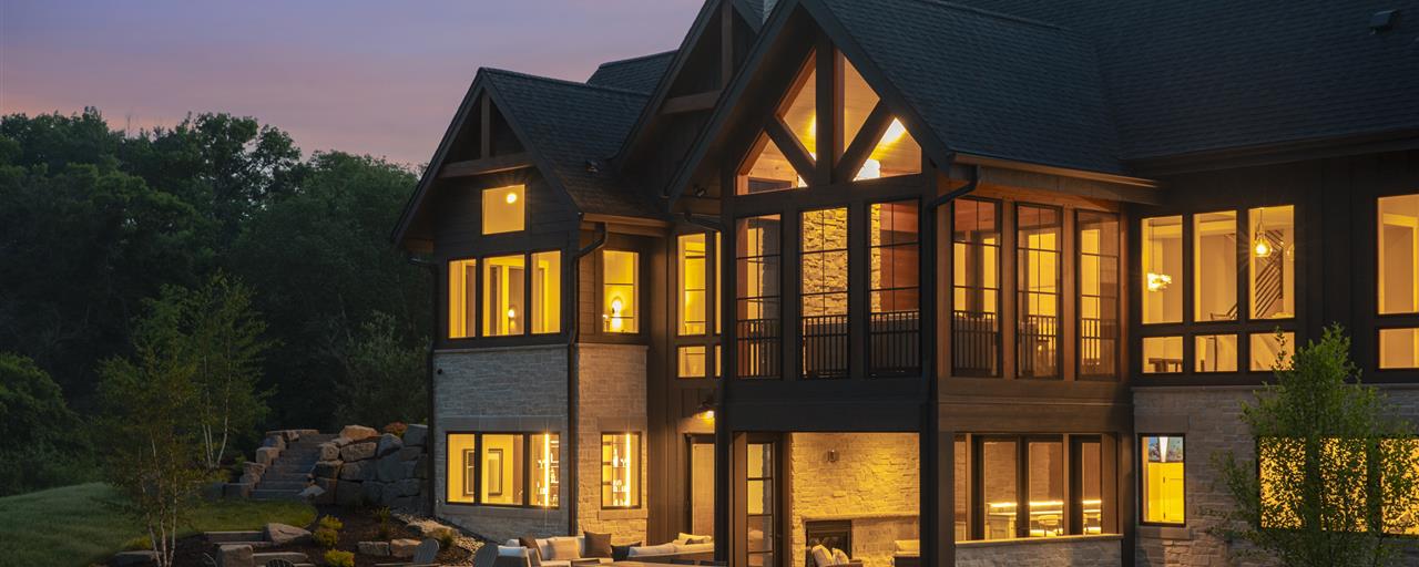 Elegant suburban home with wooden facade and large windows at twilight.