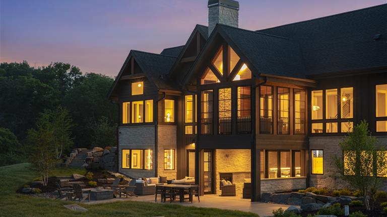 Elegant suburban home with wooden facade and large windows at twilight.