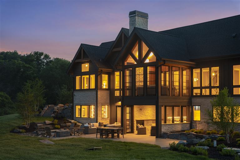 Elegant suburban home with wooden facade and large windows at twilight.