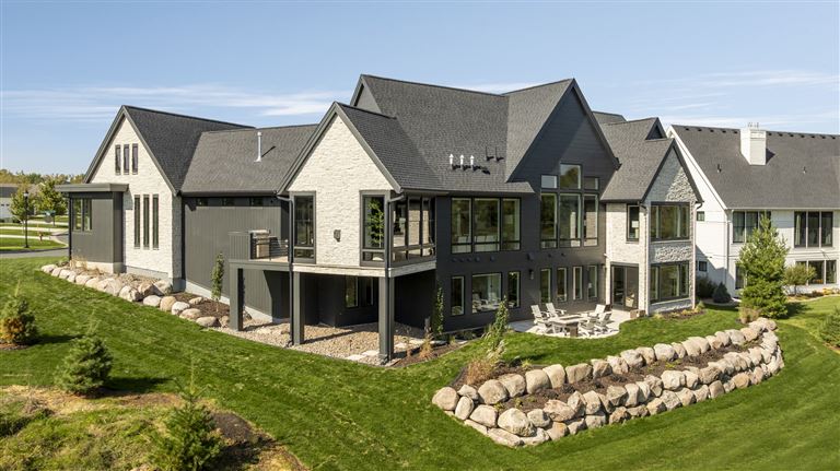 Modern upscale suburban home with a spacious lawn and driveway.