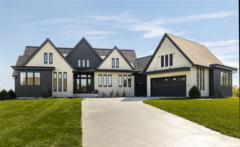 Upscale suburban home with a driveway and lawn.