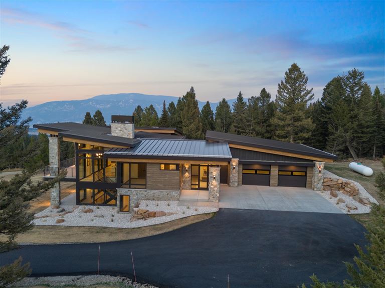 Wooden chalet in a snowy landscape with trees and clear sky.