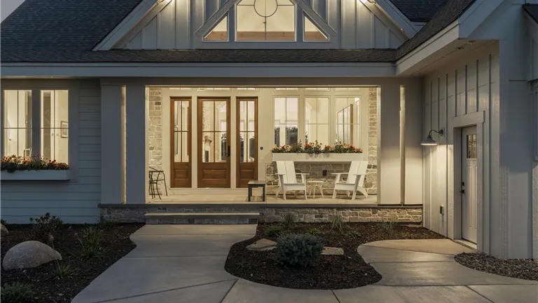 Front exterior of a luxury suburban home with a porch and elegant doorway.