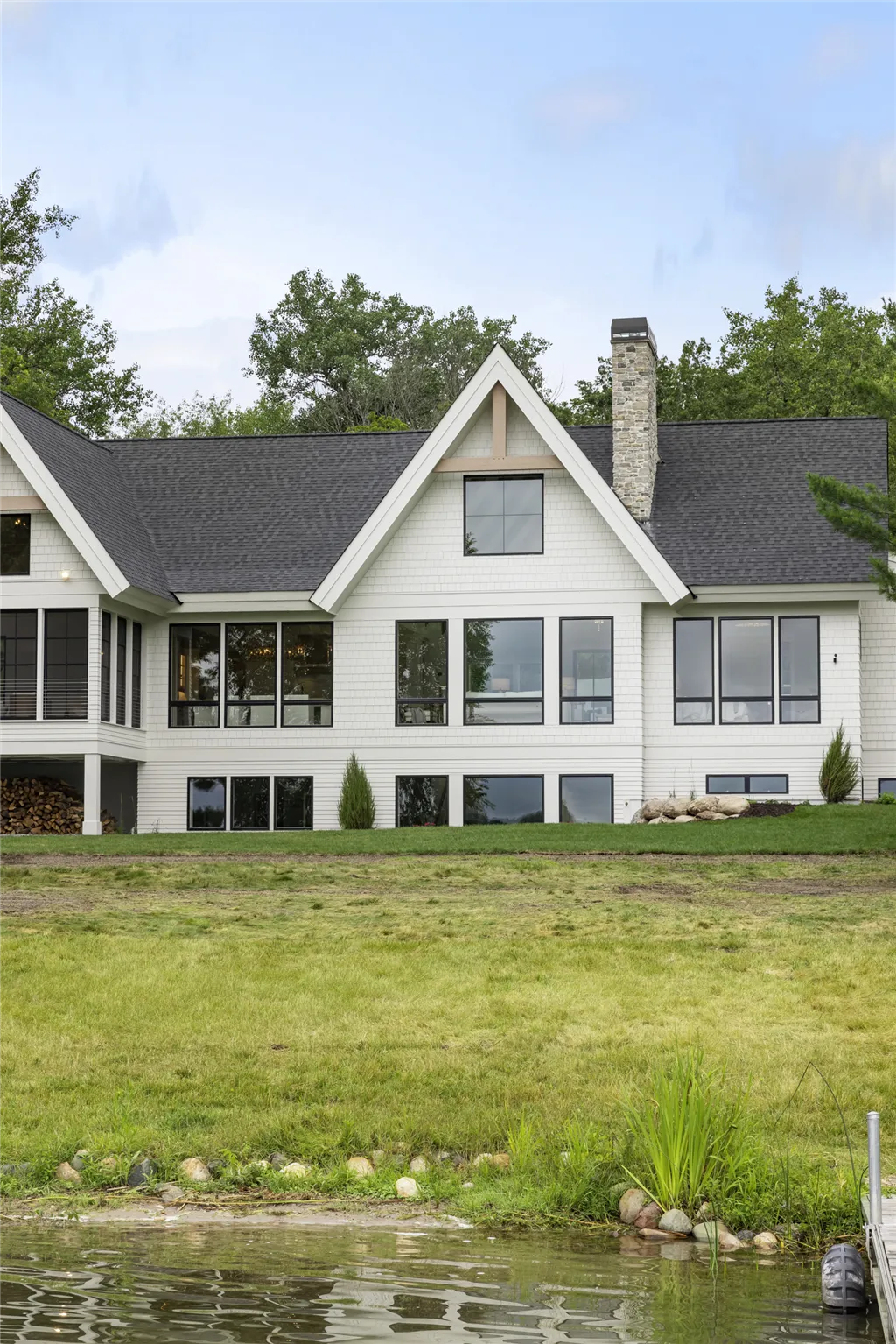 Exterior view of a luxury suburban mansion with a large lawn and garden.