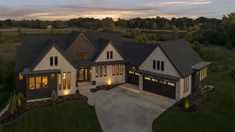 Charming suburban bungalow with a spacious driveway and lush greenery.