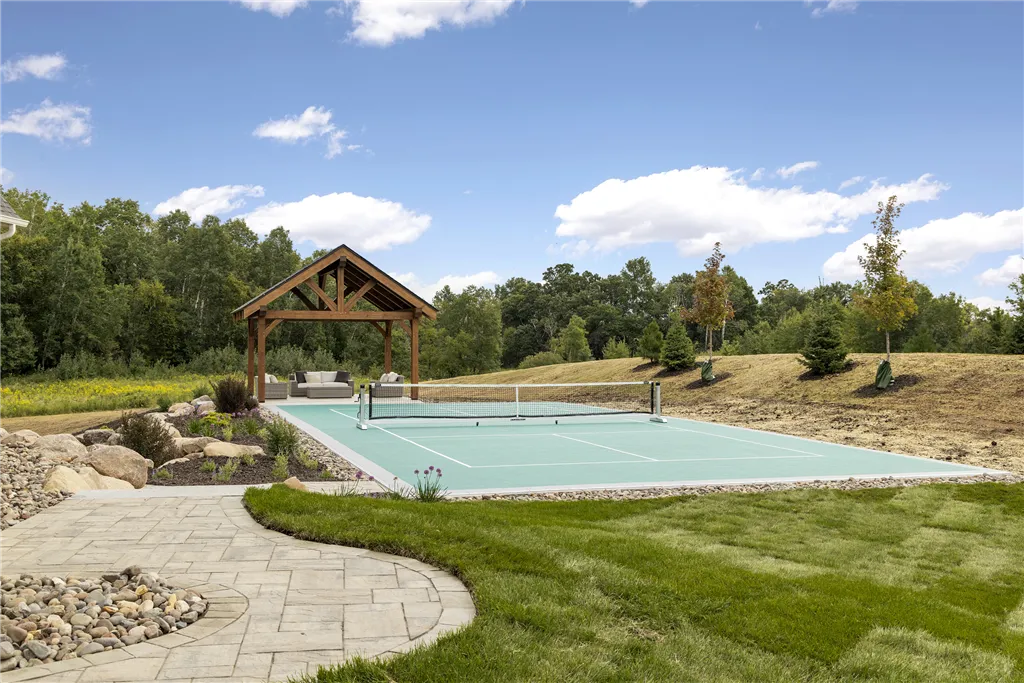 Summer garden with trees, grass, and a house at Hartman Homes.