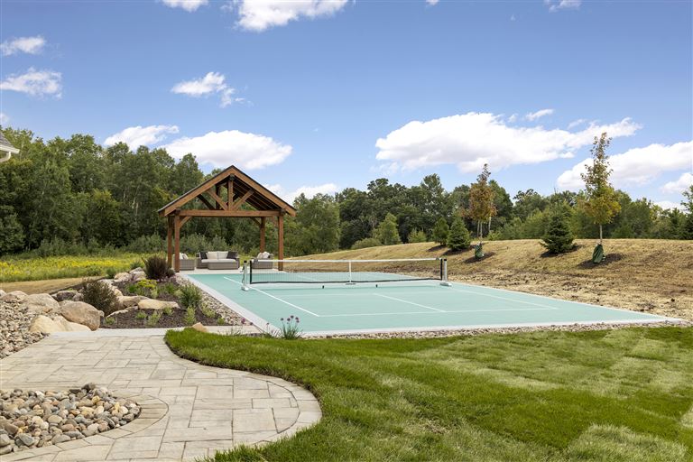 Summer garden with trees, grass, and a house at Hartman Homes.