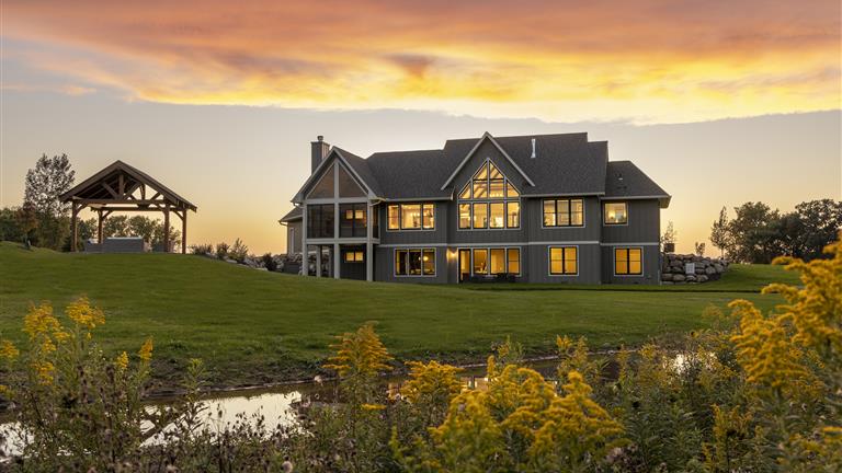 Countryside bungalow at sunset with a vibrant sky and lush grass.