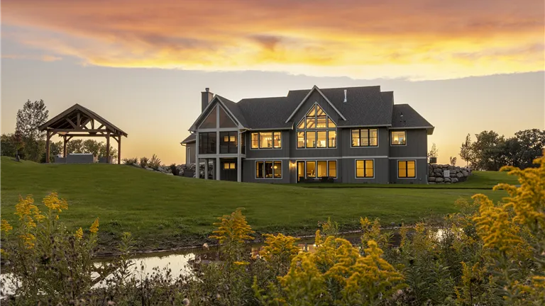 Countryside bungalow at sunset with a vibrant sky and lush grass.