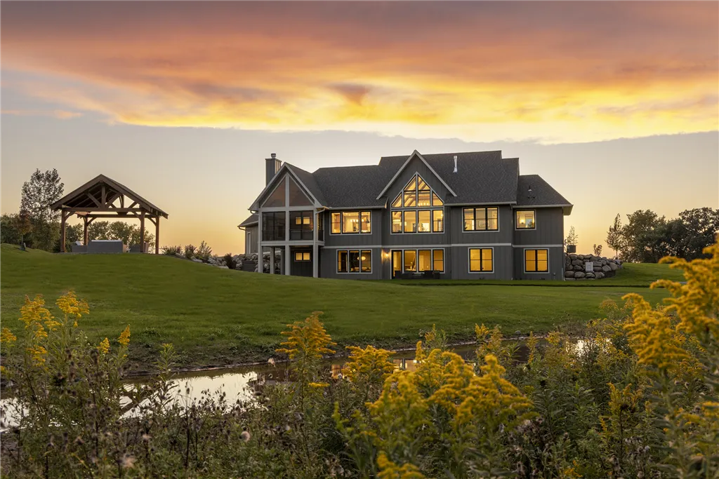 Countryside bungalow at sunset with a vibrant sky and lush grass.