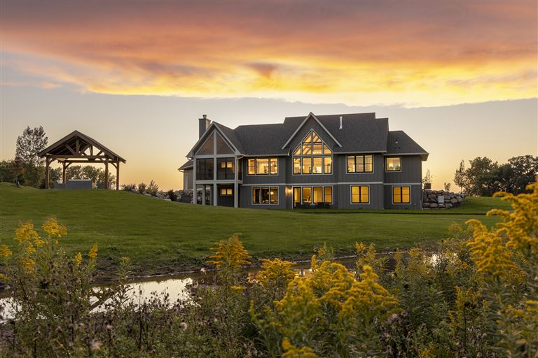Countryside bungalow at sunset with a vibrant sky and lush grass.