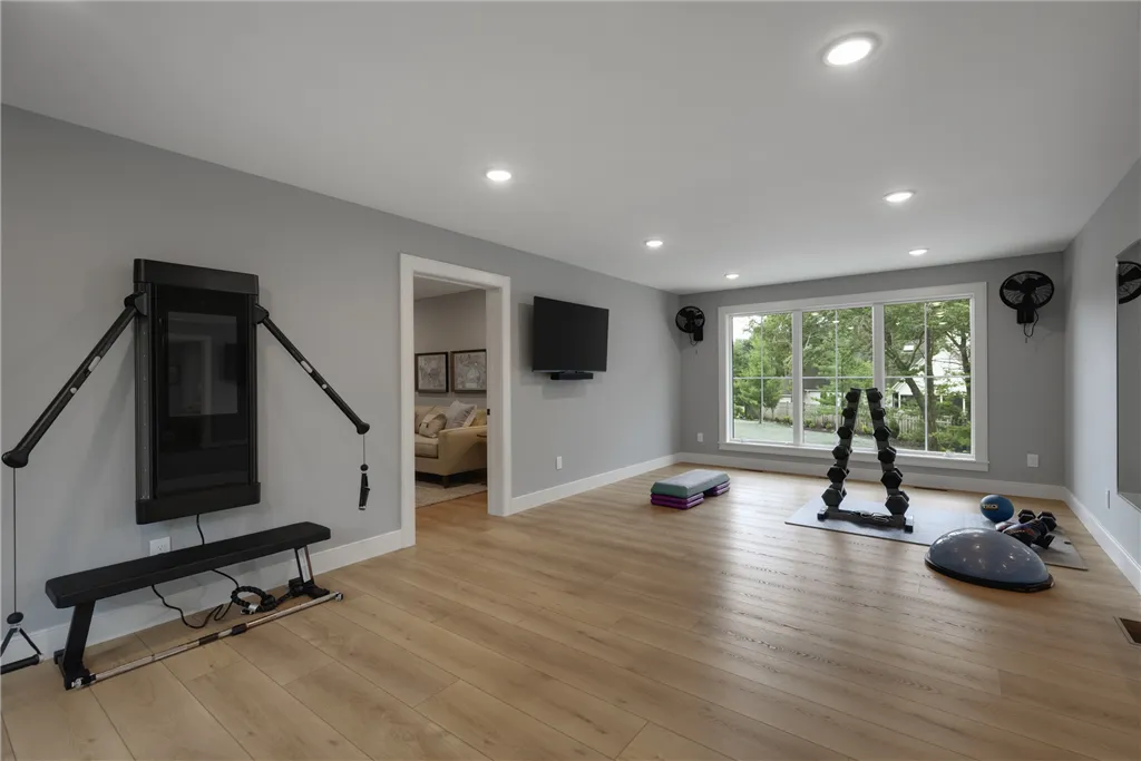 Minimalist contemporary living room with parquet flooring, a chair, rug, and fireplace.