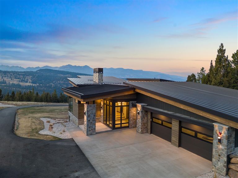 Wooden house with snow-covered roof at sunset in a winter landscape.