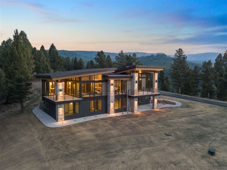Wooden cabin in a snowy landscape surrounded by trees.
