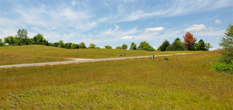 A rural landscape with fields and farmland under a clear sky.