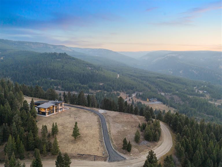 Scenic view of a mountain valley at sunset with snow-capped peaks and a winding road.
