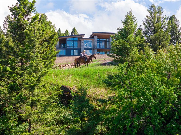 A scenic view of a farmhouse amidst a lush green landscape in summer.