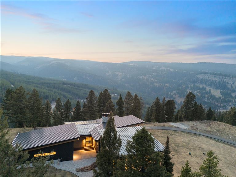 Snowy mountain landscape with a chalet by a lake at sunset.