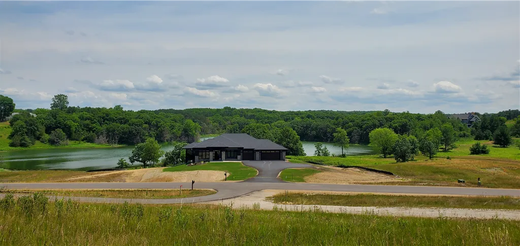 A peaceful rural landscape with a farmhouse, barn, and green fields under a blue sky.