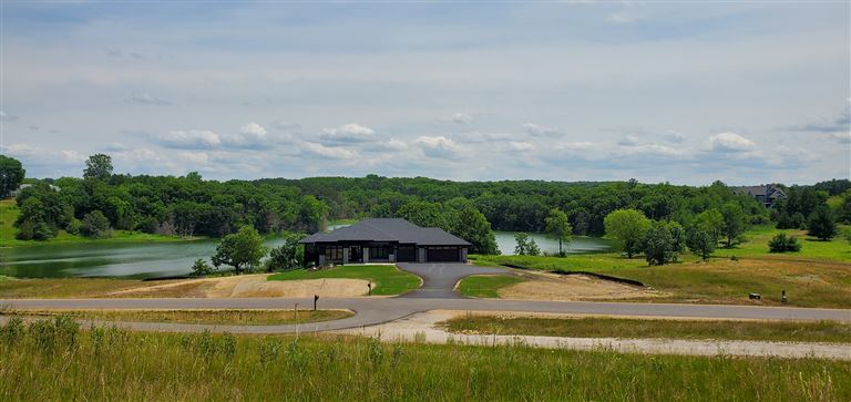 A peaceful rural landscape with a farmhouse, barn, and green fields under a blue sky.