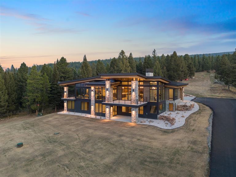 Wooden cabin in a mountainous landscape surrounded by trees.